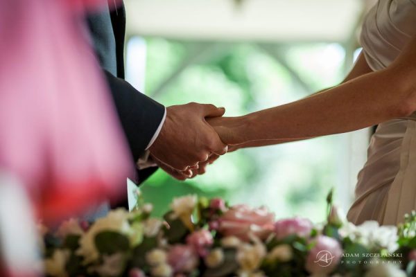 married couple hold their hands during the wedding
