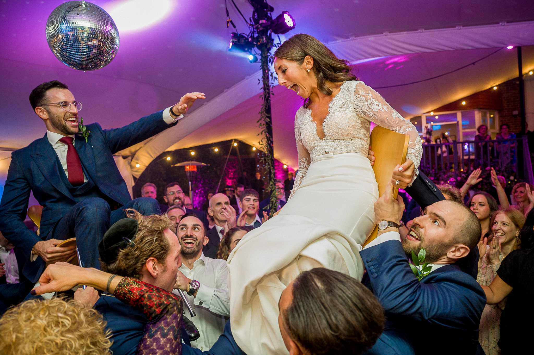 Jewish bride and groom up in the air on the chairs during Israeli dance
