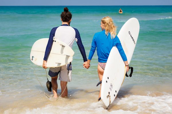 destination wedding photographer couple is walking with the surf boards