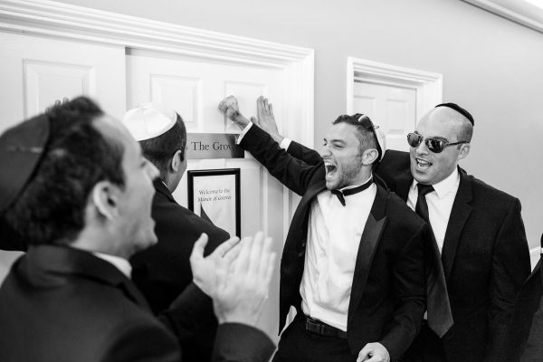 jewish wedding photographer groomsmen knock on the door