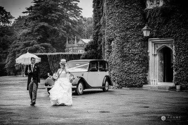 married couple walking next to their wedding car in fron of the St Audries Park