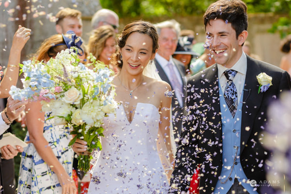 Cambridge wedding photographer couple under confetti shower 
