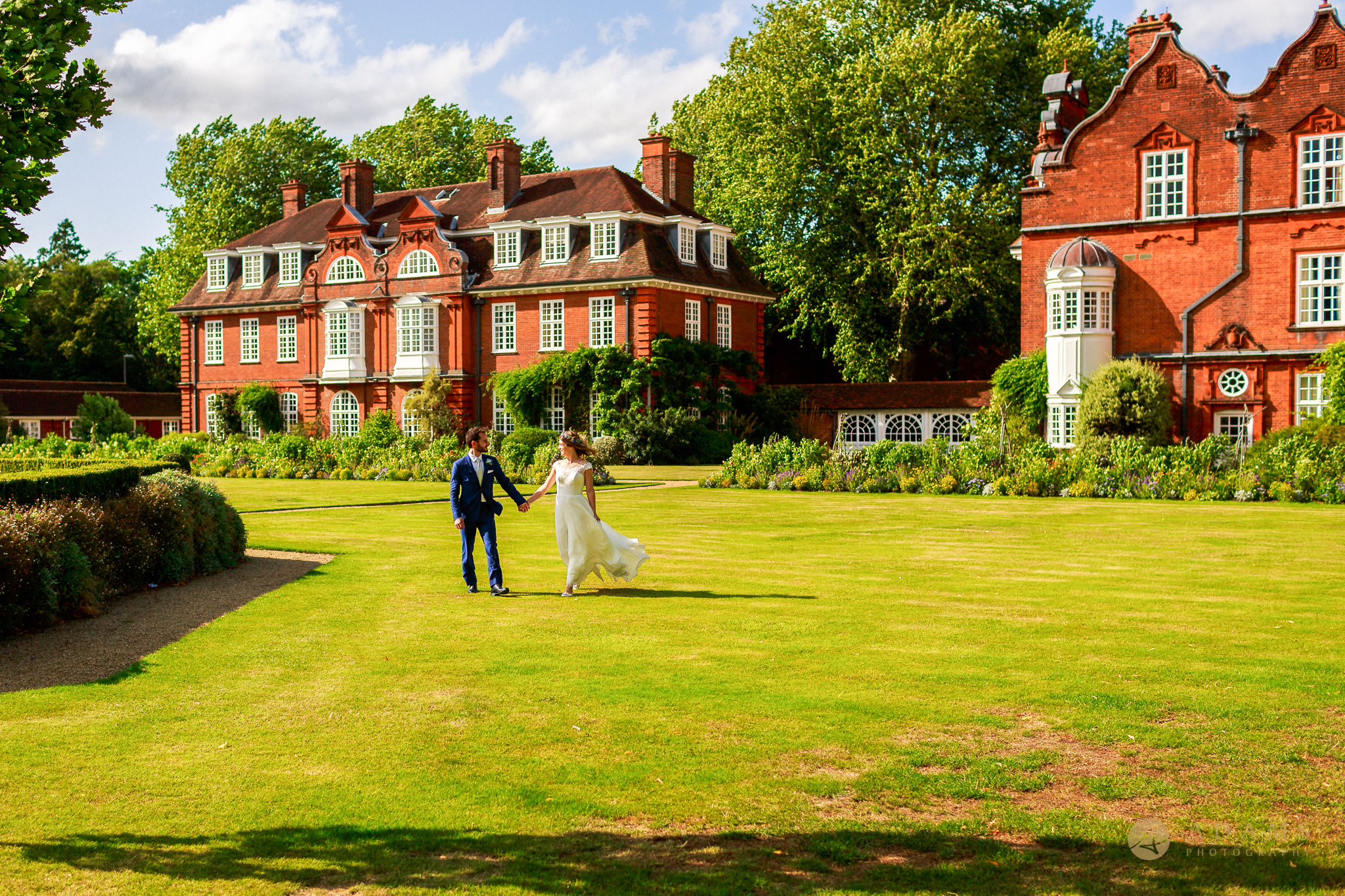 bride and groom walk on the grounds of Newnham College