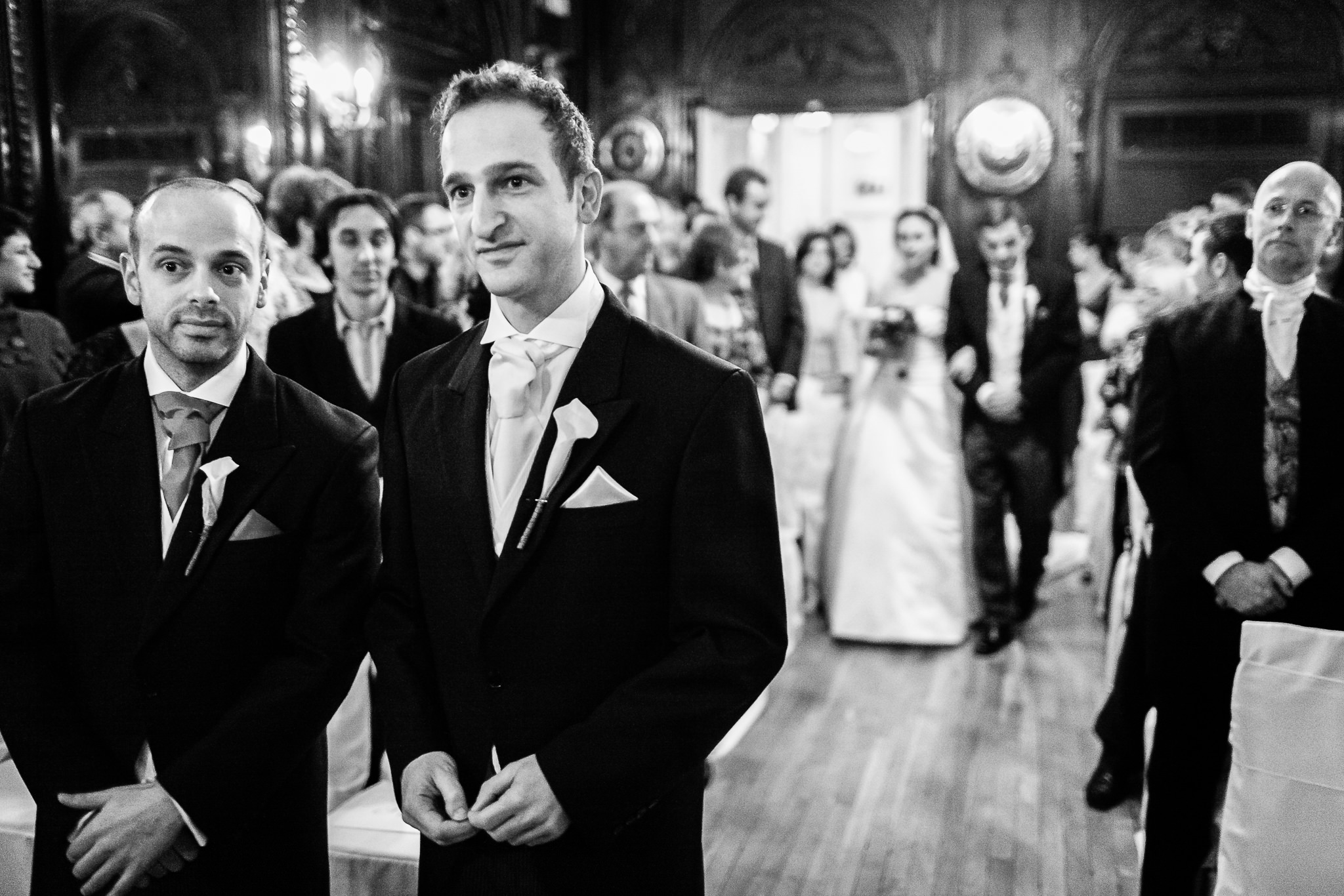 groom looks into the mirror to see the bride walking down the aisle