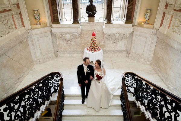 married couple by the cake on the staircase at Dartmouth House Wedding