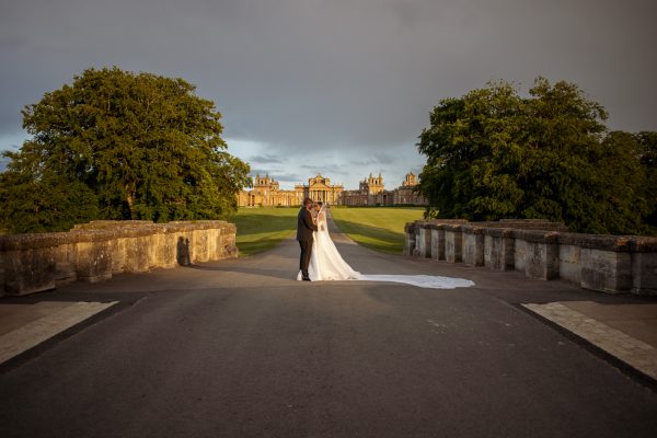 bride and groom walking on the bridge with the view of the Blenheim Palace