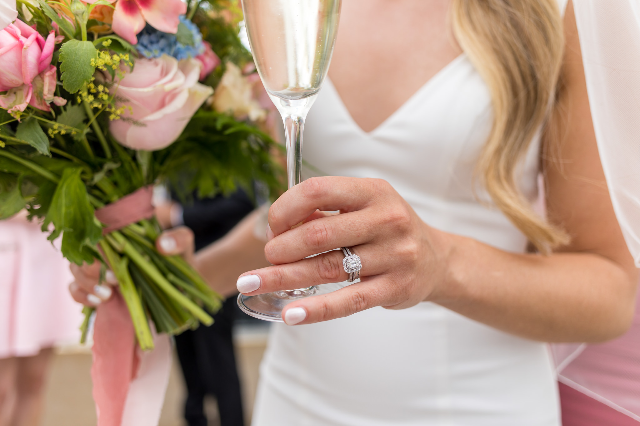 Bride holding a champagne glass , her wedding ring is visible