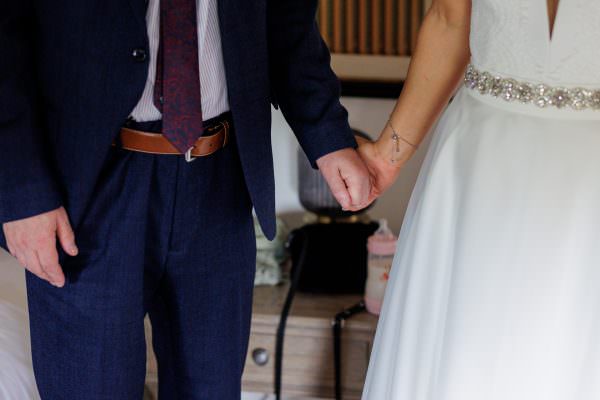 Bride holds her fathers hand.