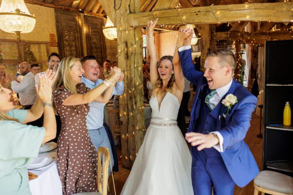 Bury Court Barn Wedding Photographer taking picture of Bride and groom holding hand in the air