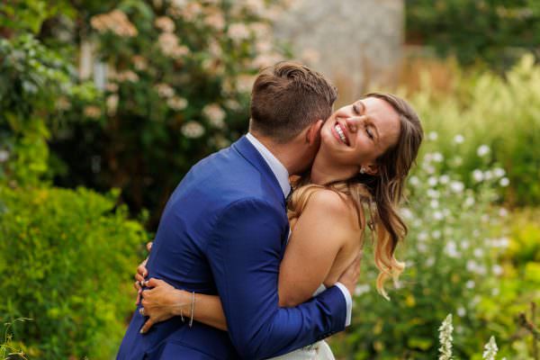 married couple hugging each other in the gardens of the Bury Court Barn