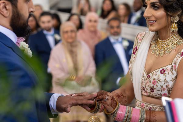 Bridal putting a ring on grooms hand