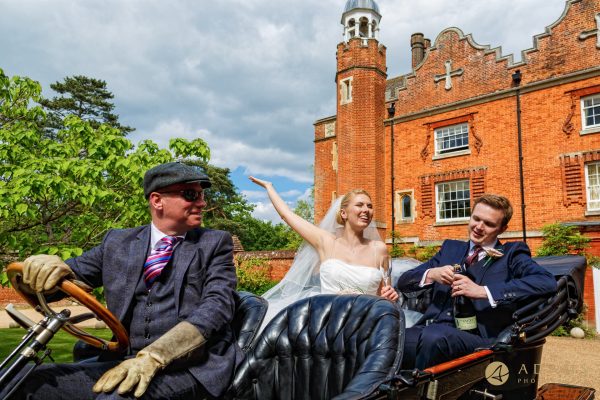 Bride and groom open champagne on the vintage car