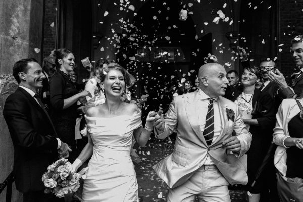 bride and groom running thought confetti
