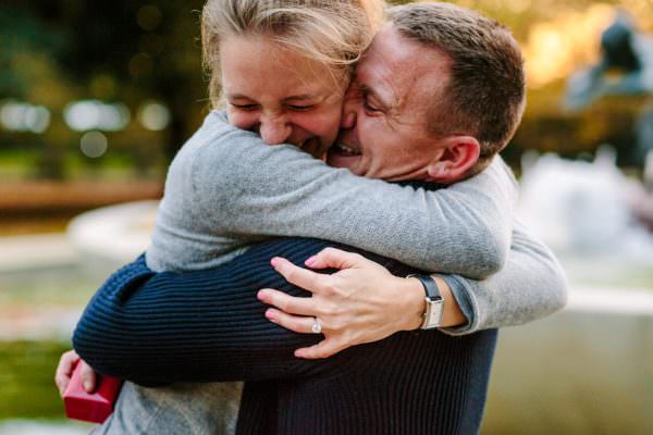 a girlfriend is huge a boyfriend with beautiful smile on her face after the surprise proposal in Hyde Park London