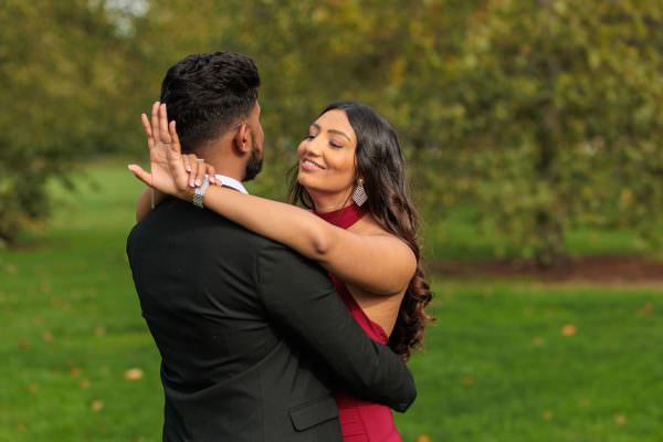 Fiance is admiring her engagement ring while being hugged by her boyfriend after the proposal in Hyde Park