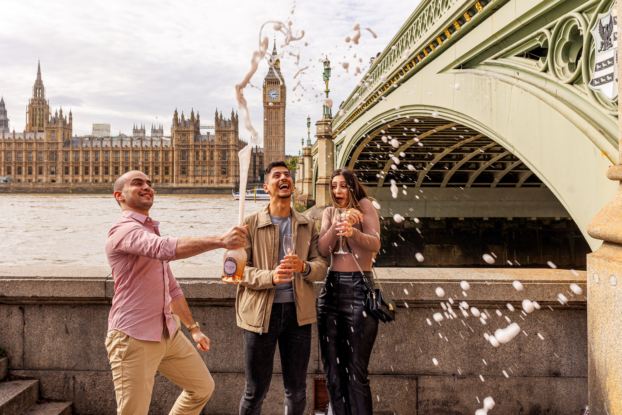 Moments after the proposal with Big Ben and Houses of Parliament a freind is opening a champagne with excitement