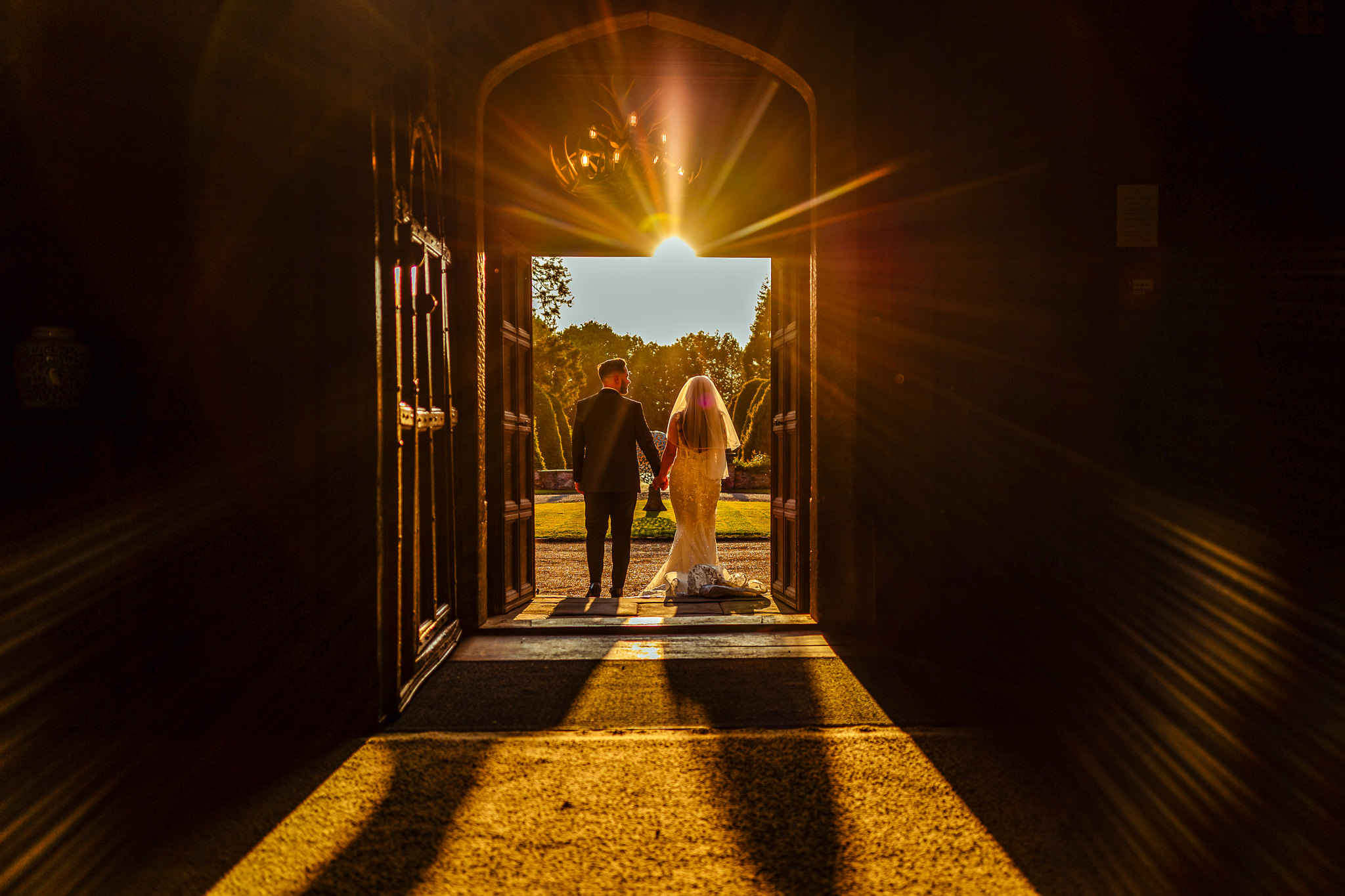 Married couple going out form the Great Fosters Hotel Door in the Sun Rays